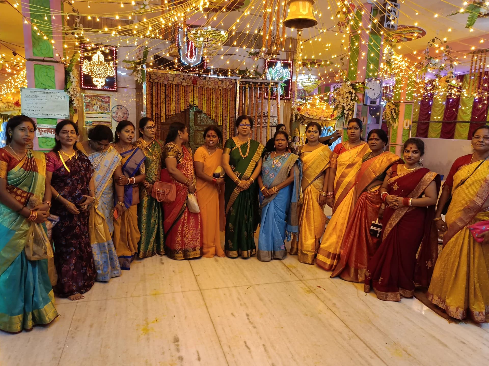 Members of the temple community standing together in the decorated prayer hall.