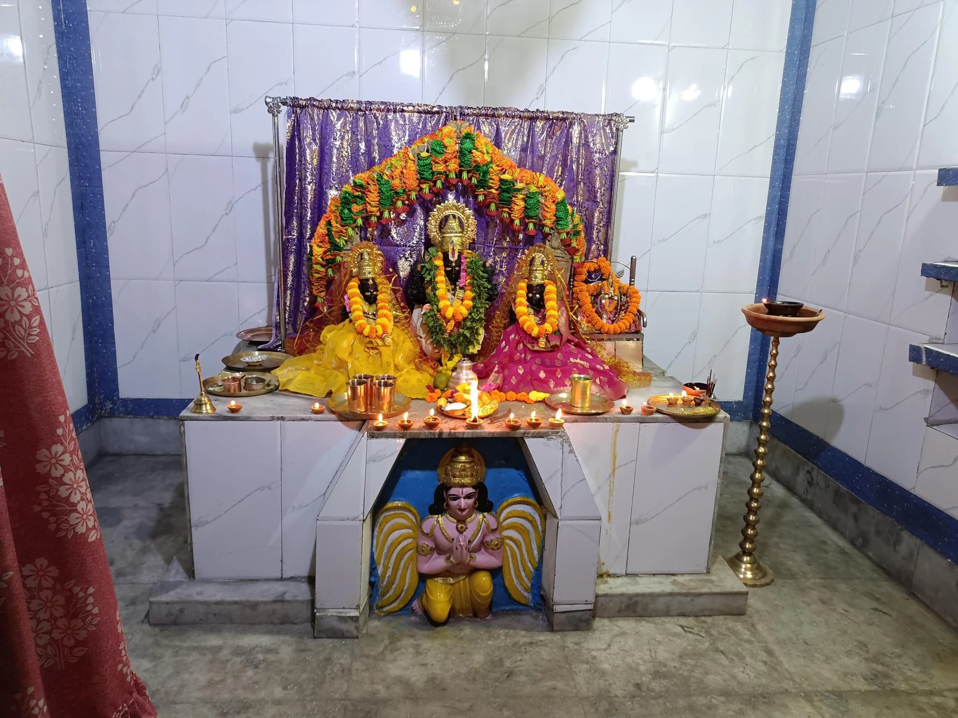 Interior shrine at Sri Venkateswara Swamy Temple, Alipurduar Junction, with the principal deities framed by a floral arch.