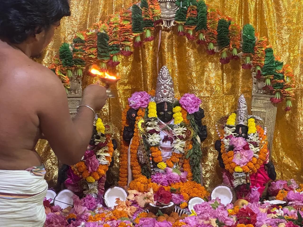 Worship at Sri Venkateswara Swamy Temple, with a lamp offered before the decorated deities